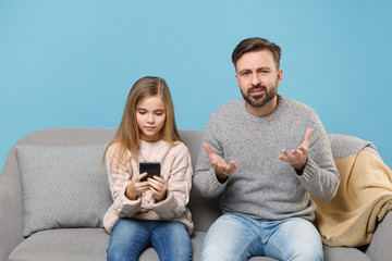 Perplexed bearded man in knitted sweater with child baby girl. Father little daughter isolated on...