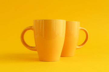 Two yellow coffee cups on yellow background