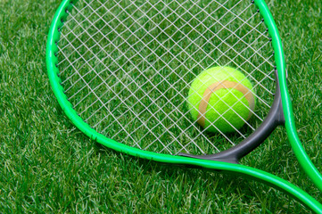 Tennis racket and ball on green grass
