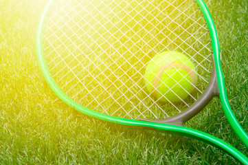 Tennis racket and ball on green grass