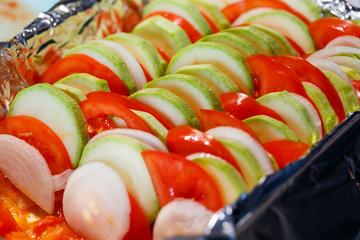 chopped vegetables tomatoes, zucchini, onions, peppers folded into a baking dish. Cooking...