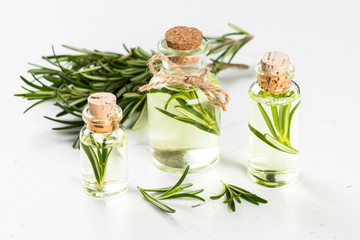 Rosemary essential oil in the bottle on white.