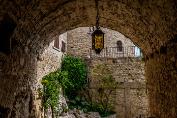 A tunnel-like passage of an old medieval town with a crafty metal lantern hanging in the middle...