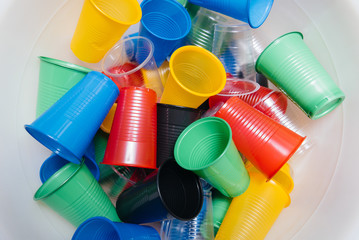 A large pile of multicolored plastic cups scattered on the floor. Pollution of the environment by...