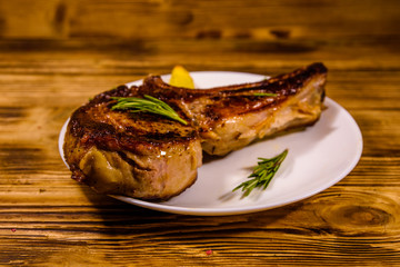 Plate with roasted ribeye steak and potatoes on wooden table