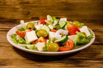 Ceramic plate with greek salad on wooden table