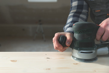 Carpentry. Wood sanding. Orbital sander for woodworking. In a natural light