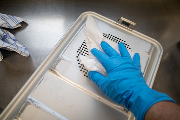 in  operating theatre an instrument container is cleaned and disinfected by one hand with blue...