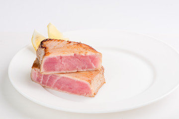 grilled tuna fish steak on a white plate with a place for garnish