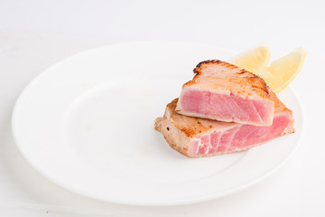 grilled tuna fish steak on a white plate with a place for garnish