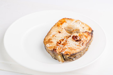 grilled fish steak on a white plate with a place for garnish