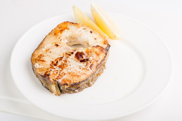 grilled fish steak on a white plate with a place for garnish