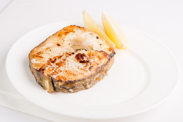 grilled fish steak on a white plate with a place for garnish