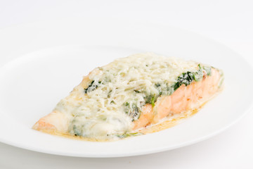 piece of salmon in a creamy sauce with spinach on a white plate