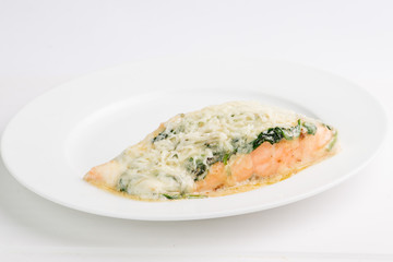 piece of salmon in a creamy sauce with spinach on a white plate