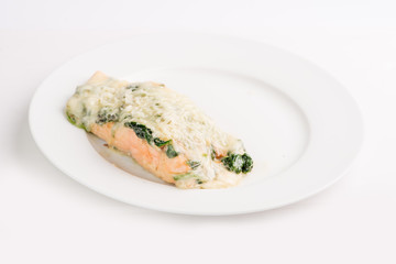 piece of salmon in a creamy sauce with spinach on a white plate