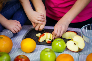 daughter and mom cut a fruit salad consisting of apple orange and mandarin