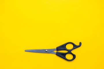 Black scissors on a yellow background. Top view. Copy, empty space for text