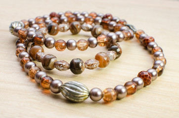 Multicolored necklaces with pearls and fancy accessories on wooden background