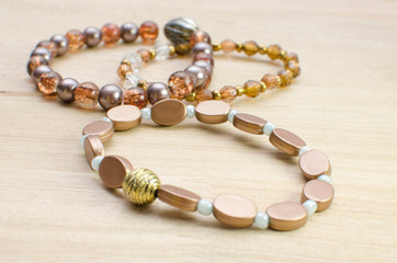 Multicolored bracelets with pearls and fancy accessories on wooden background