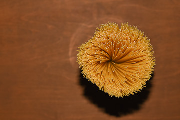top view of yellow uncooked spaghetti pasta on a brown wooden table, shooting with flash hard light, copy space for culinary recipe text or restaurant menu