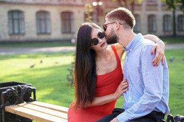 Beautiful couple of man and woman sitting on a bench in a park. Romantic theme with a girl and a guy. Spring Summer theme  relationship, love, Valentine's day