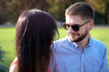 Beautiful couple of man and woman sitting on a bench in a park. Romantic theme with a girl and a guy. Spring Summer theme  relationship, love, Valentine's day