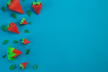 paper strawberries with sheets of paper on a light blue background