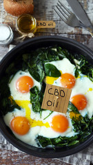 Selective focus. The inscription cbd oil in food. Spinach eggs with cannabis oil. CDB use of oil concept.