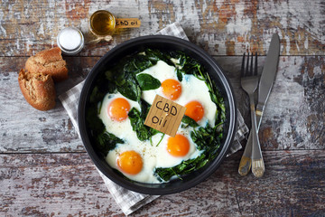 Selective focus. The inscription cbd oil in food. Spinach eggs with cannabis oil. CDB use of oil concept.