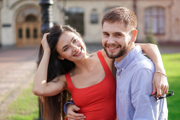Naklejka premium Beautiful couple of man and woman sitting on a bench in a park. Romantic theme with a girl and a guy. Spring Summer theme relationship, love, Valentine's day