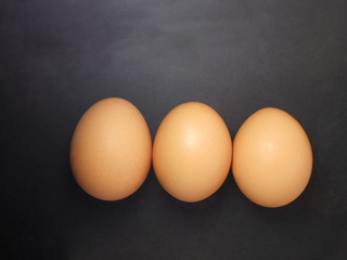 Raw chicken eggs on black background. top view