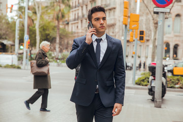 boy walking with blue suit and calling by phone in city