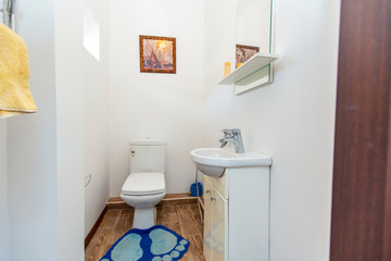 Bathroom in the guest house in a white tile with a toilet and sink