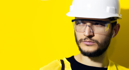 Studio close-up portrait of young confident man architect, builder engineer, wearing white...