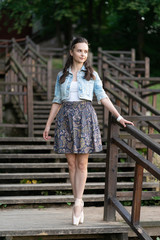 Beautiful young girl ballerina in pointe shoes walks on the stairs in the summer park