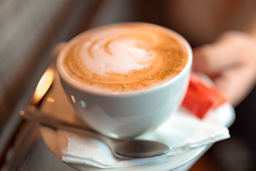 cup of coffee with cream on wooden background