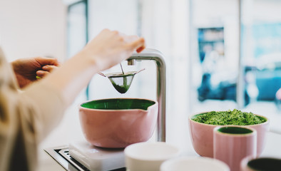 Barista sieving a matcha powder while traditional tea ceremony using modern tea ware set. Woman's...