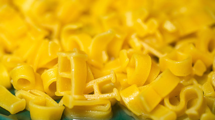 macaroni alphabet letters on a green plate.