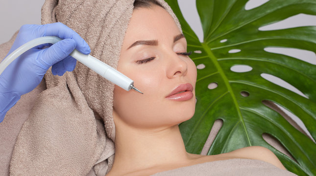 The cosmetologist makes the procedure treatment of Couperose and face cleaning of the skin of a beautiful, young woman in a beauty salon.Cosmetology and professional skin care.