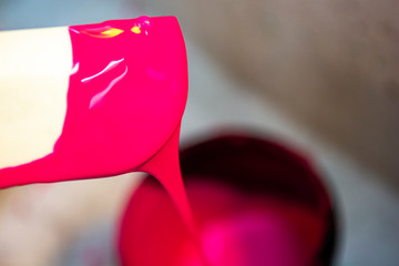 Dripping pink emulsion liquid on a spatula, thick and creamy