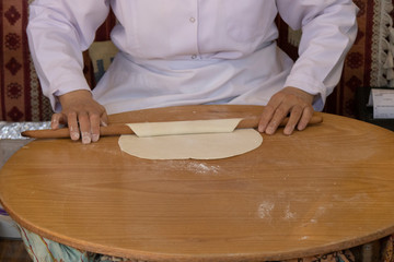 Woman rolls out dough, close-up. Making Turkish traditional flat cakes.