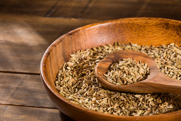 Dried fennel seeds in a wooden bowl with wooden spoon - Foeniculum vulgare