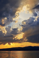 Landscape with a dramatic fiery sunset on the Black Sea coast. The rays of the sun make their way through the clouds