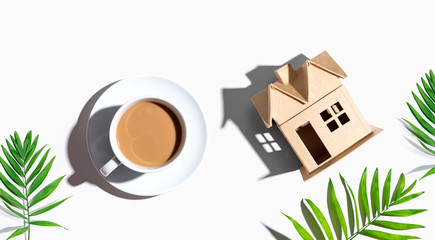 Cardboard house with a cup of coffee - flat lay