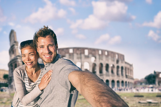 Rome tavel selfie couple taking photo with phone at colosseum famous landmark, Italy. Europe summer vacation young people smiling. Backpacking road trip.