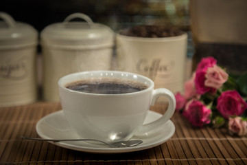 big cup of coffee, flowers and coffee beans in a can