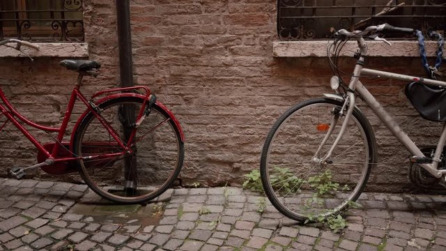 Two old classic bikes red and white parked near ancient brick wall, detail view