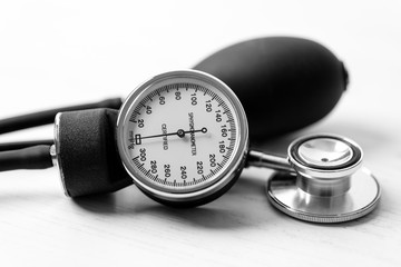 sphygmomanometer and stethoscope on white wooden desktop.
