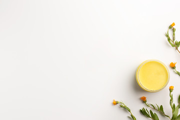 Organic cosmetic concept. Flowers of calendula and jar of skin care cream, isolated on white...
